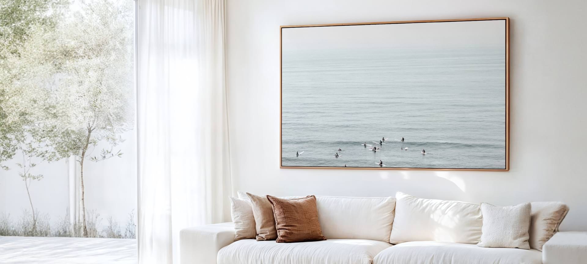 Framed photo of surfers hanging on the wall of a sunlit room.
