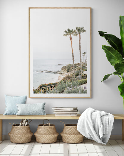 Vertical coastal photography featuring a scenic view of the ocean with palm trees in the background, set against a white sky, located in Laguna California. Photograph in minimalist mock up.