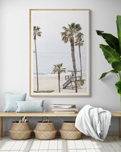 Vertical coastal photography of a coastal scene with palm trees and a lifeguard tower at Aliso Beach, Laguna California, with a wooden frame. Photograph in minimalist mock up.