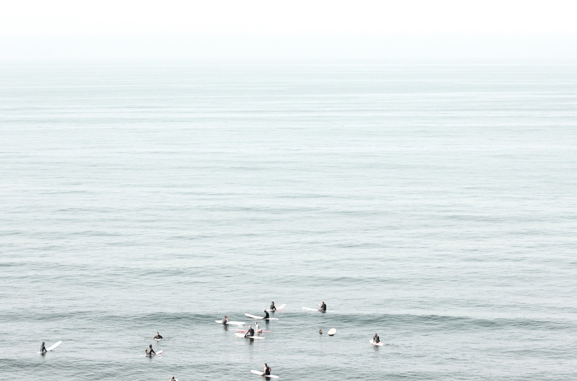 Photography by Kim Dybczak of: Surfers gather offshore at California, spaced out on the calm lineup.