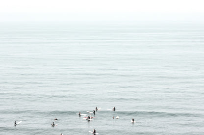 Photography by Kim Dybczak of: Surfers gather offshore at California, spaced out on the calm lineup.
