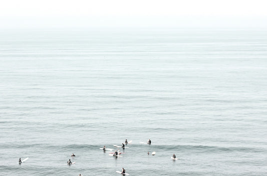 Photography by Kim Dybczak of: Surfers gather offshore at California, spaced out on the calm lineup.