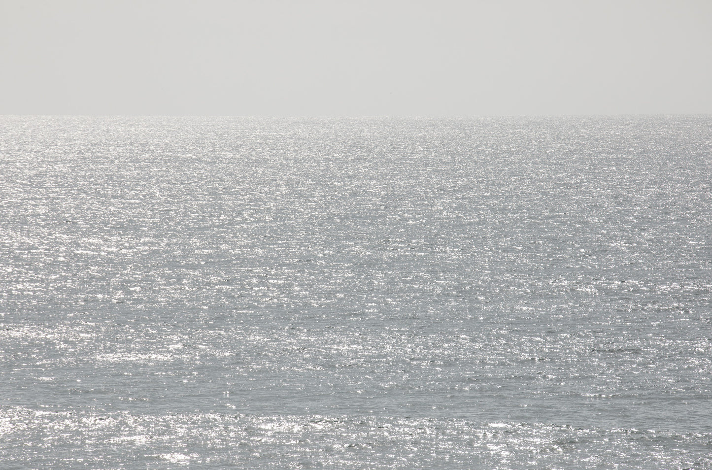 Photography by Kim Dybczak of: The coast shoreline stretches wide, with gentle waves smoothing the sand.