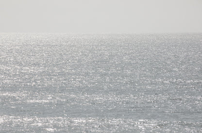 Photography by Kim Dybczak of: The coast shoreline stretches wide, with gentle waves smoothing the sand.