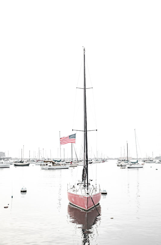 Photography by Kim Dybczak of: A sailboat drifts offshore at San Diego, framed by wide sky and calm water.