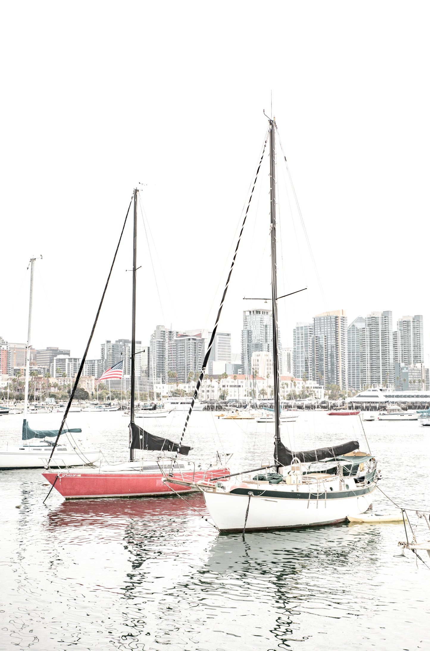 Photography by Kim Dybczak of: A sailboat drifts offshore at San Diego, framed by wide sky and calm water.