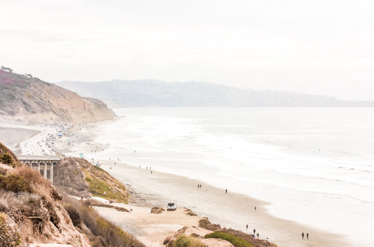 Photography by Kim Dybczak of: Hazy high-angle beach scene on the San Diego coast, with waves meeting a busy sandy shore.