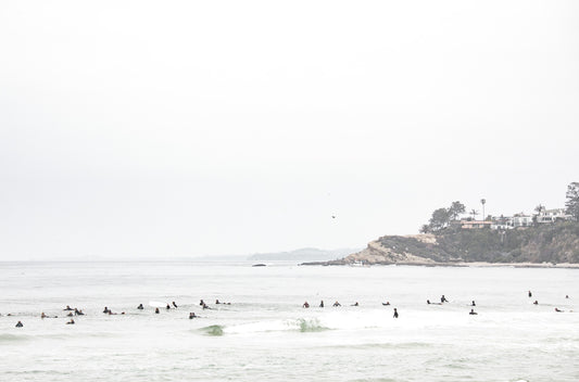 Photography by Kim Dybczak of: Surfers paddle out at Salt Creek as waves rise and fold toward the beach.