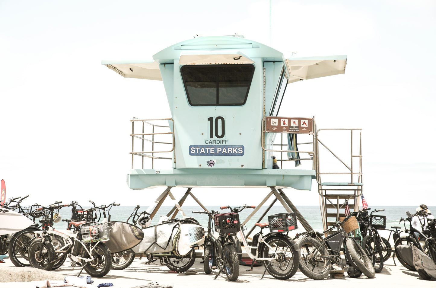 Photography by Kim Dybczak of: San Diego lifeguard tower stands near the shoreline, framed by sand and quiet surf.