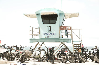 Photography by Kim Dybczak of: San Diego lifeguard tower stands near the shoreline, framed by sand and quiet surf.