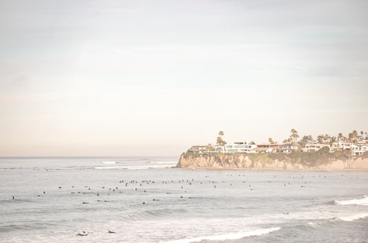 Photography by Kim Dybczak of: Surfers gather offshore at San Diego, spaced out on the calm lineup.