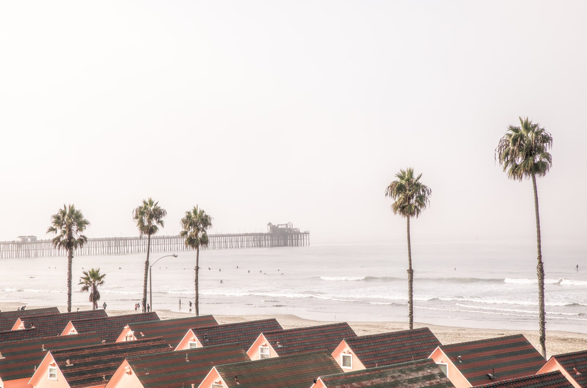 Photography by Kim Dybczak of: California pier extends beyond the surf, framed by sky and steady waves.