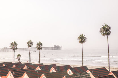 Photography by Kim Dybczak of: California pier extends beyond the surf, framed by sky and steady waves.