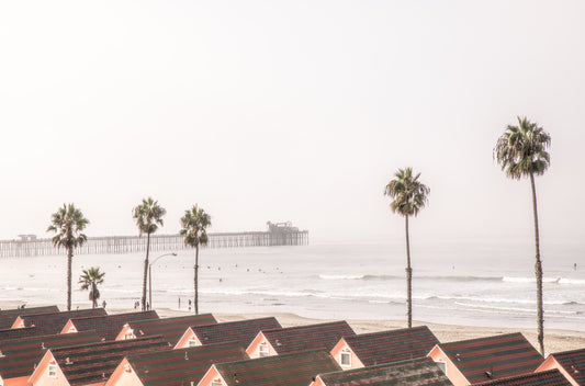 Photography by Kim Dybczak of: California pier extends beyond the surf, framed by sky and steady waves.