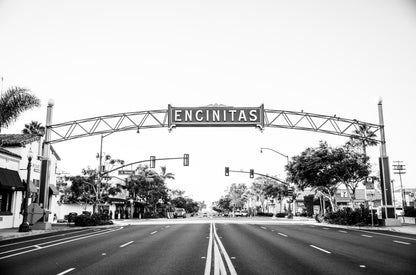 Photography by Kim Dybczak of: An Encinitas street sign stands against a city street background.