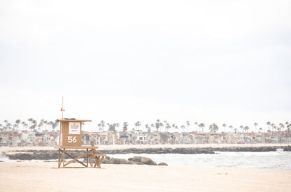 Photography by Kim Dybczak of: A lifeguard tower anchors the coast, set against calm water and open sky.