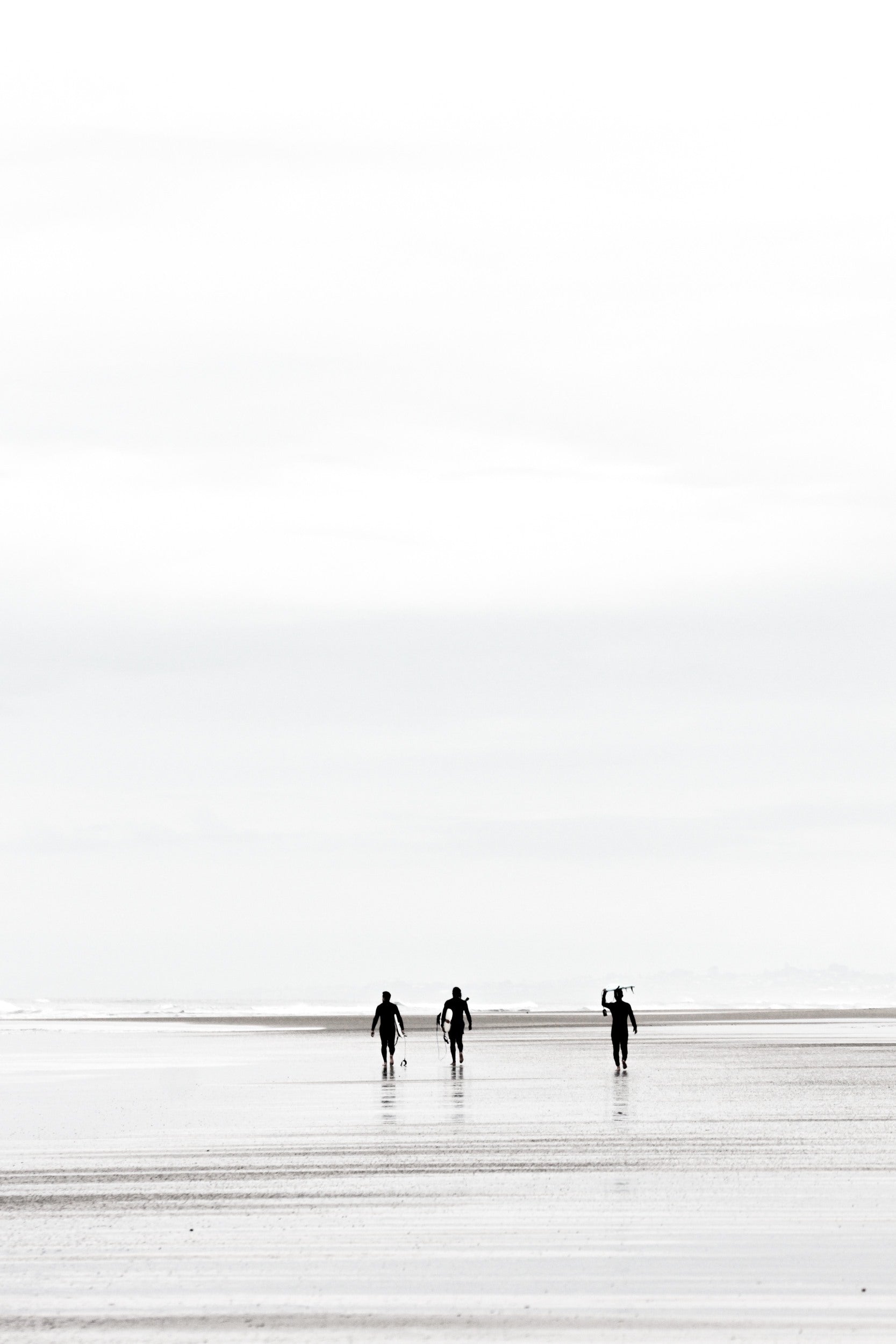 Surfers carrying surfboards on the sand at Black’s Beach, black and white, by Salt Creek Prints
