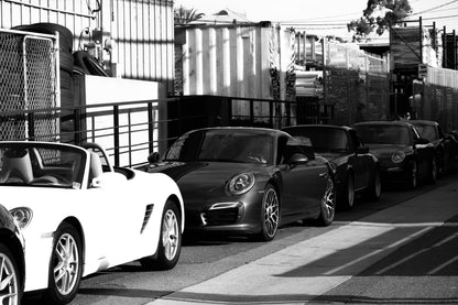 Photography by Salt Creek Prints of: Porsche 8352, Black and white image of a row of modern Porsches lined up in an alley.