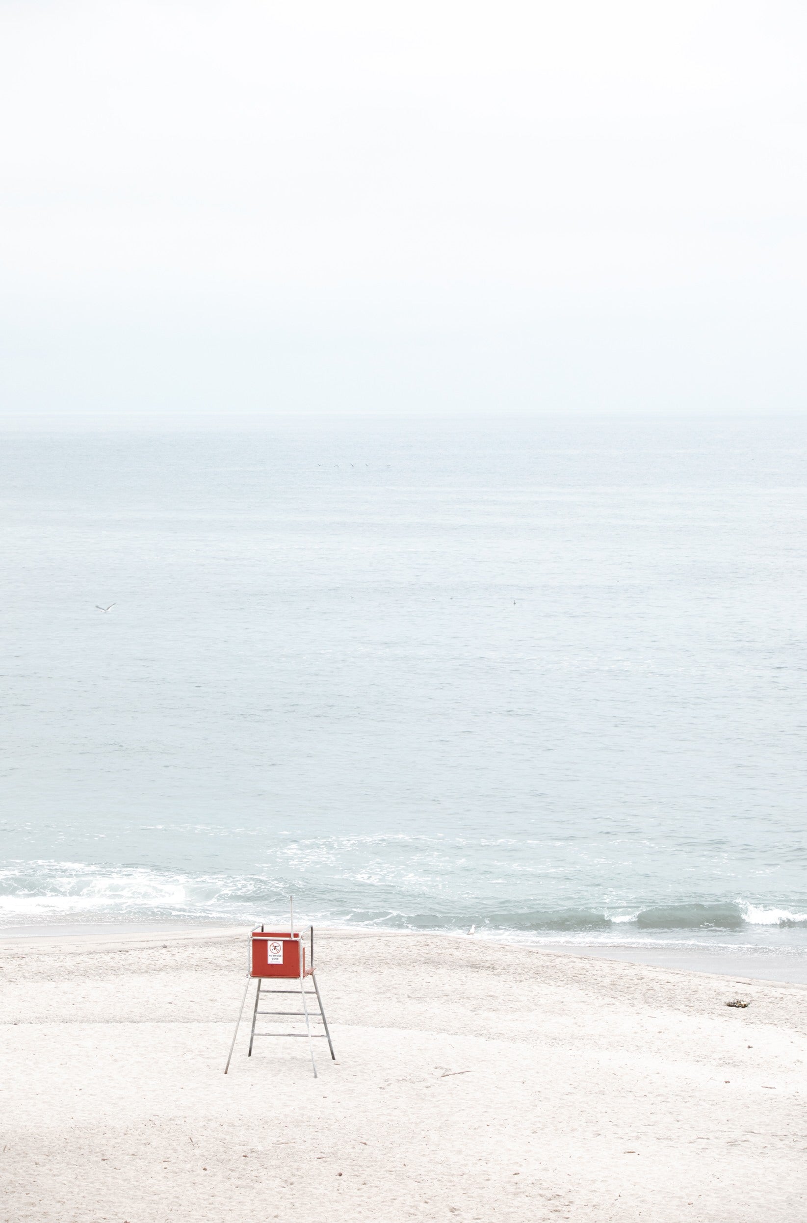 Photography by Kim Dybczak of: Laguna lifeguard tower stands near the shoreline, framed by sand and quiet surf.