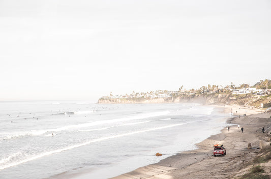 Photography by Kim Dybczak of: Surfers gather offshore at Pacific Beach below a residential cliffside in San Diego.