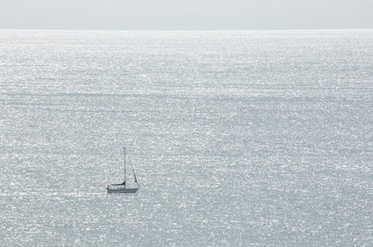 Photography by Kim Dybczak of: A lone sailboat glides on open water near San Diego, standing out against the sea.