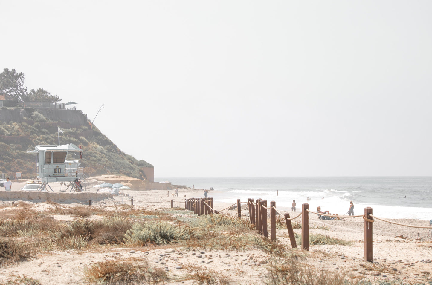 Photography by Kim Dybczak of: California lifeguard tower stands near the shoreline, framed by sand and quiet surf.