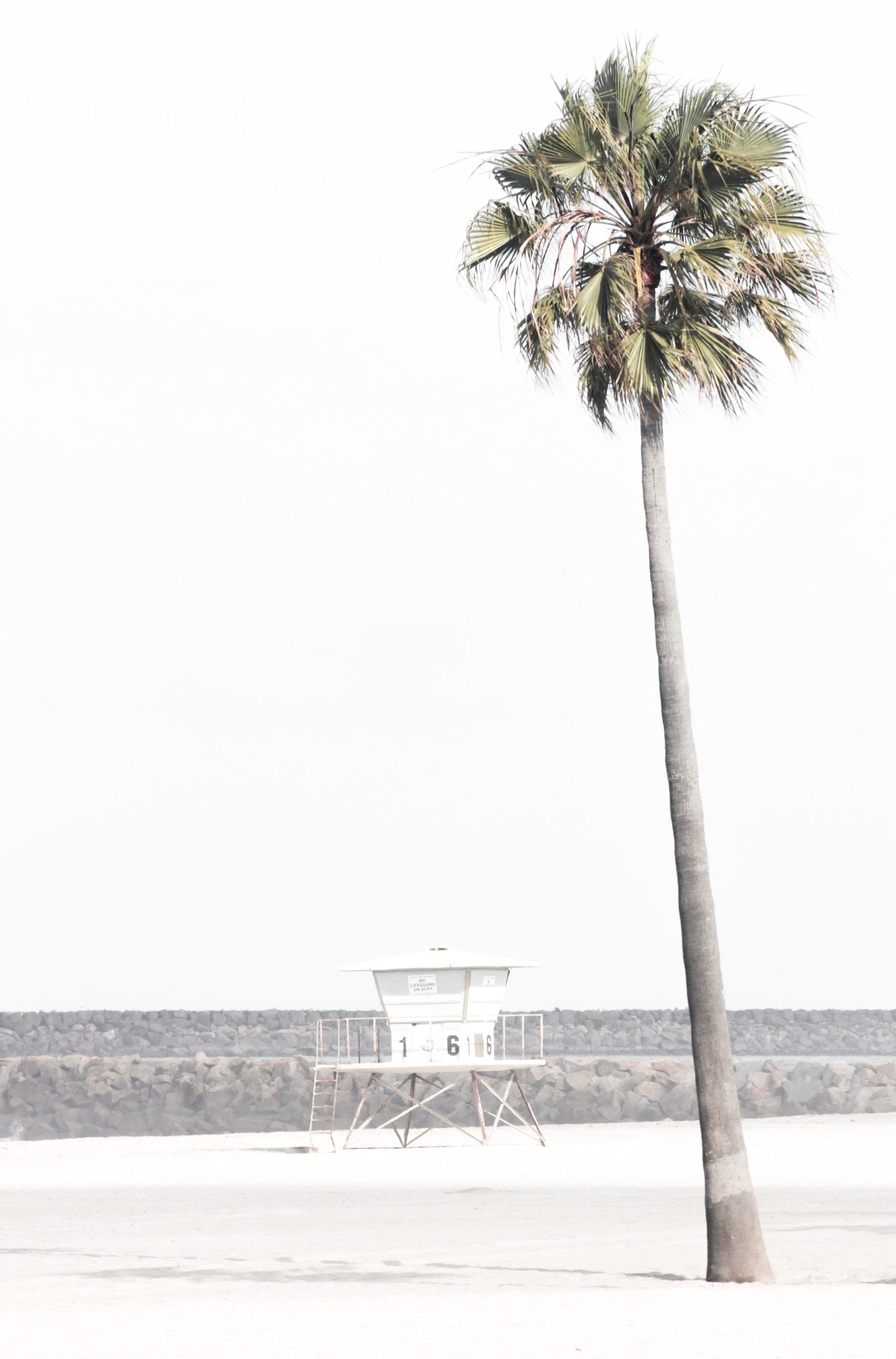 Photography by Kim Dybczak of: A California lifeguard tower set against calm water and open sky, softened by coastal haze.