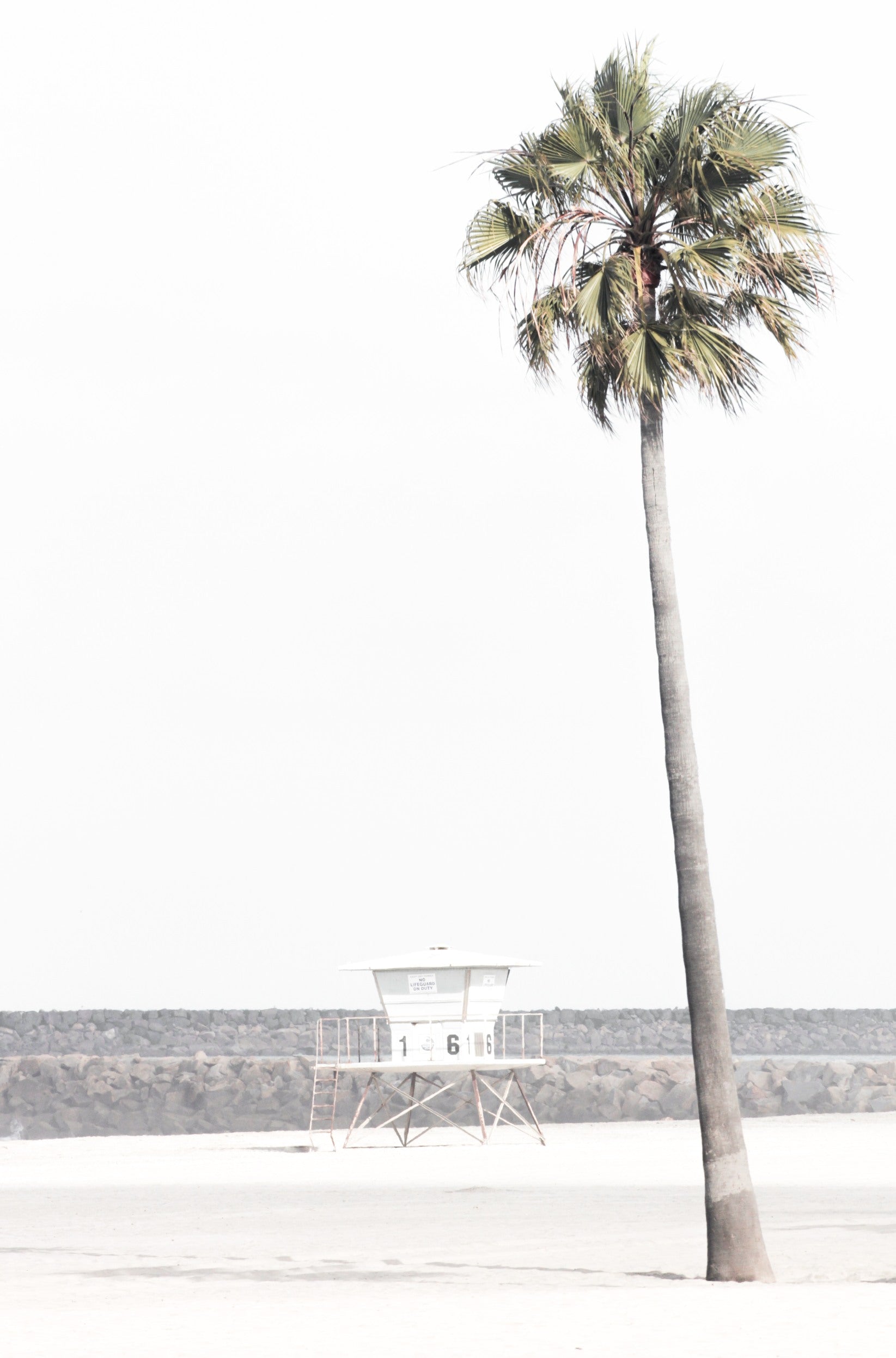 Photography by Kim Dybczak of: A California lifeguard tower set against calm water and open sky, softened by coastal haze.