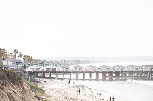 Photography by Kim Dybczak of: A busy public beach in San Diego fills with people along the shoreline and in the water.
