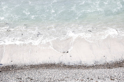 Photography by Kim Dybczak of: A rocky shoreline meets foamy waves along a rugged stretch of coast.