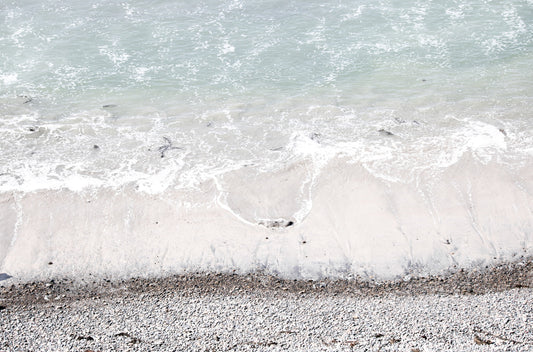 Photography by Kim Dybczak of: A rocky shoreline meets foamy waves along a rugged stretch of coast.