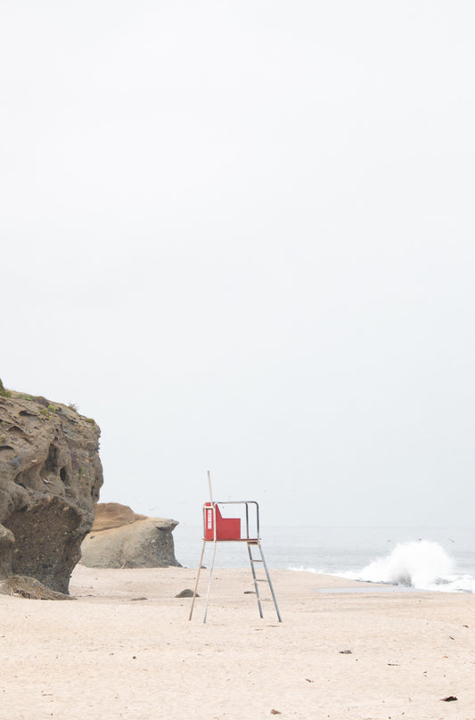 Photography by Kim Dybczak of: Laguna lifeguard tower stands near the shoreline, framed by sand and quiet surf.