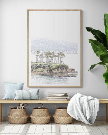 Vertical coastal photography of Laguna Beach, San Diego, featuring a fine art giclee print featuring palm trees on a small island in a body of water. Photograph in minimalist mock up.