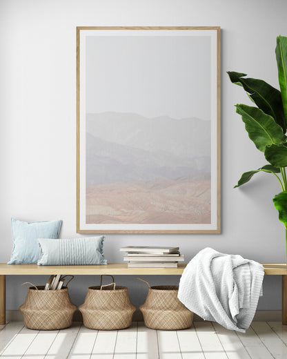 Minimalist art print of hazy mountains layered in soft tones, creating a calm ocean print aesthetic. This vertical minimalist art print can fit a neutral ocean print theme. Photograph in minimalist mock up.