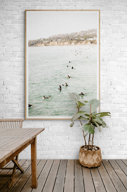 Vertical surf print showing several surfers paddling in the ocean at Pacific Beach, with a distant coastline. This image captures the surfing art of Southern California. Photograph in minimalist mock up.