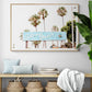 Colorful travel photography capturing the iconic 'Solana Beach' sign, a quintessential piece of Surf Signs San Diego art. The retro light blue sign, adorned with white cursive script and a unique steer head logo, is set against a backdrop of towering palm trees and a bright, hazy California sky. This Southern California surf beach sign evokes strong summer vibes and is perfect for coastal decor. Photograph in minimalist framed entry way mock up.