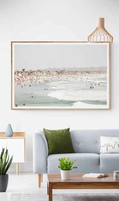 Landscape beach photography of a busy San Diego public beach with many people in the sand and ocean waves, a true summer vibes scene. Photograph in minimalist mock up.